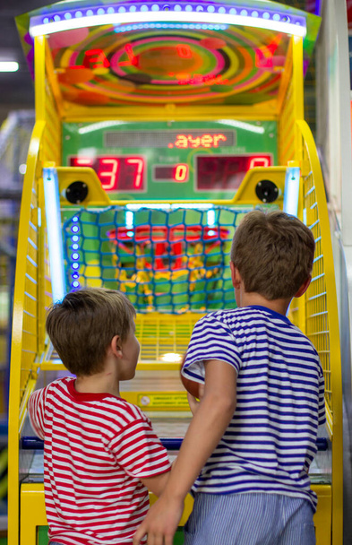 Eğlence merkezi ve kumar makineleri olan çocuk bölgesi. İki çocuk basketbolu sepete atıyor. Basketbol atari oyunu.  - Fotoğraf, Görsel