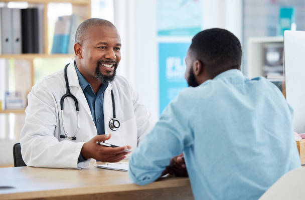 Szczęśliwy, rozmowy i lekarz z czarnym mężczyzną na opiekę zdrowotną, wsparcie i porady dotyczące leczenia. Uśmiech, konsultacja i afrykański gp z pacjentem mówiącym o medycynie, zdrowiu i profesjonalnej pomocy. - Zdjęcie, obraz