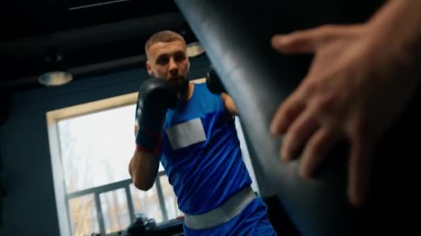 bokserski siłownia a bokser trenuje jego ciosy uderzenie worek - Materiał filmowy, wideo