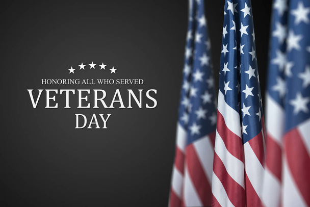 American flags with Text Veterans Day Honoring All Who Served on black background. American holiday banner. - 写真・画像