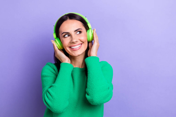 Photo of dreamy shiny lady dressed green sweater arms hands headphones looking empty space isolated violet color background. - Foto, Bild