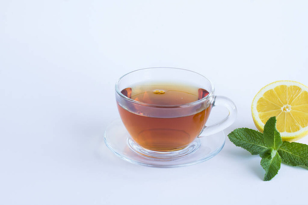 Fekete tea az üvegpohárban, citrom és menta a fehér háttérben. Másold a helyet. Közelkép. - Fotó, kép