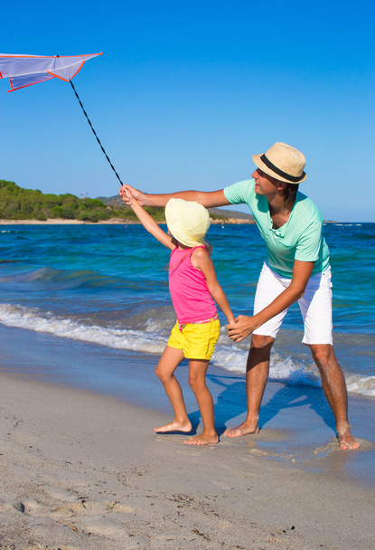 Щасливий батько і маленька дівчинка грають з змієм під час літніх канікул на пляжі
 - Фото, зображення