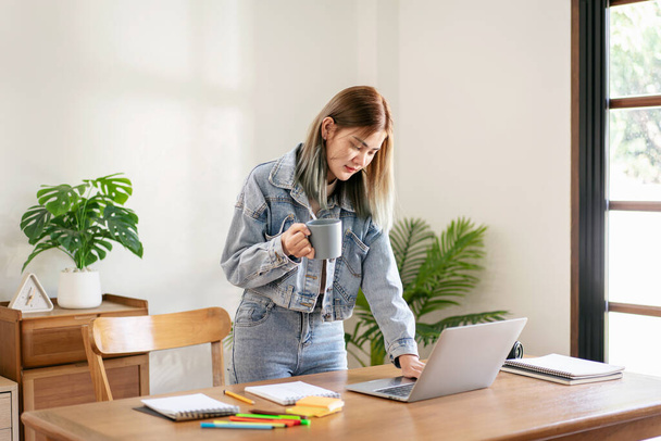 Kobiecy artysta mody relaks i zrobić przerwę od picia kawy podczas pracy na laptopie i projektowanie nowej mody w studio warsztatowym. - Zdjęcie, obraz