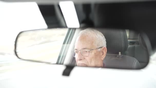 wideo starego emeryta widzianego w przednim lusterku, uważnego na drogę i bardzo poważnego, osoby powyżej osiemdziesięciu lat, w dobrym zdrowiu, noszącego okulary. - Materiał filmowy, wideo