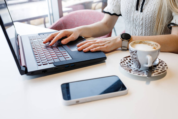 Egy lány programozni tanul egy csésze kávé mellett egy kávézóban. Távolsági tanulás - Fotó, kép