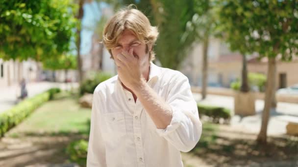 Młody człowiek cierpiący na brzydki zapach w parku - Materiał filmowy, wideo