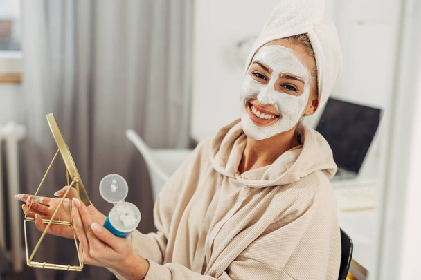 A happy Caucasian woman with a face mask looks at the camera and smiles - Photo, Image
