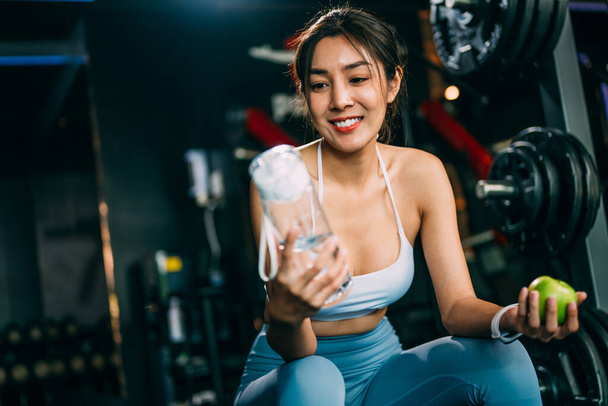 Portrait of female athlete replenishing water balance after fitness workout at gym, Healthy woman relaxing after exercises workout and training with weightlifting in fitness sport club, Healthy - Foto, imagen