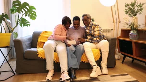 madre incinta con nonni sul divano, afroamericani, stanno guardando l'ecografia del bambino - Filmati, video