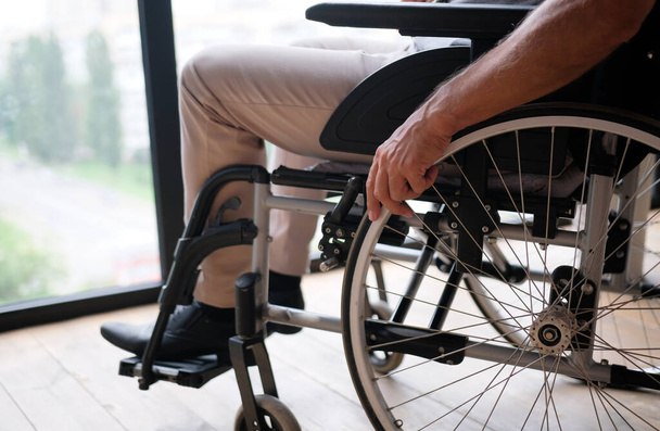 Close up view elderly male hand on rotary ring of self-propelled wheelchair. Concept of movement disorder loss of muscle function caused by age, senile disease, accident - Φωτογραφία, εικόνα