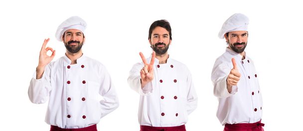 Chef-kok doet overwinning gebaar op witte achtergrond - Foto, afbeelding