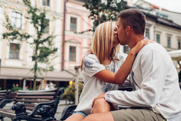 Retrato de pareja joven enamorada besándose en la vieja ciudad de Lviv usando camisas tradicionales ucranianas bordadas. Feliz hombre y mujer teniendo una cita romántica - Foto, imagen