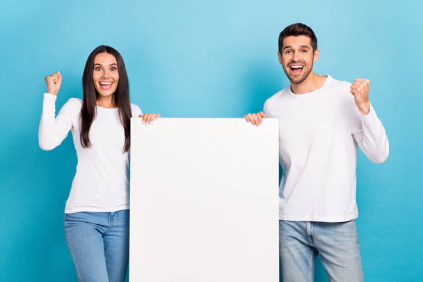 Photo of two delighted overjoyed people raise fists empty space blank isolated on blue color background. - Foto, Bild