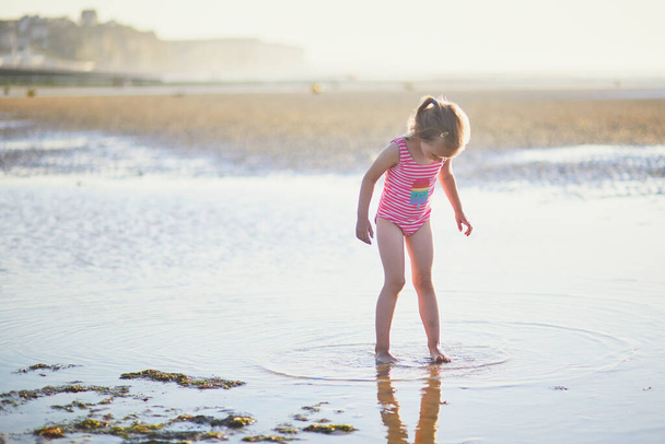 Το κορίτσι του νηπιαγωγείου διασκεδάζει στην αμμουδιά στην ακτή του Ατλαντικού της Νορμανδίας, Γαλλία. Υπαίθριες καλοκαιρινές δραστηριότητες για παιδιά - Φωτογραφία, εικόνα