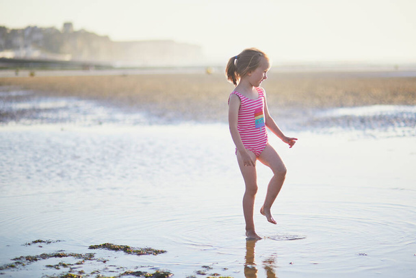 Preschooler girl having fun on the sand beach at Atlantic coast of Normandy, France. Outdoor summer activities for kids - Фото, зображення