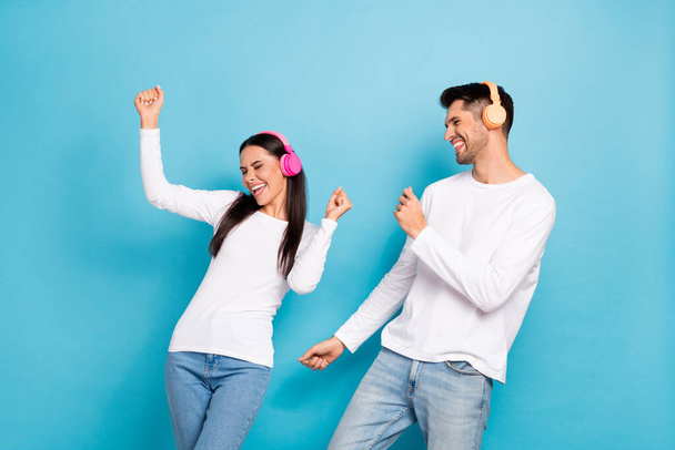 Portrait of two satisfied positive funny persons dressed white shirts dancing having fun enjoy music isolated on blue color background. - Fotó, kép