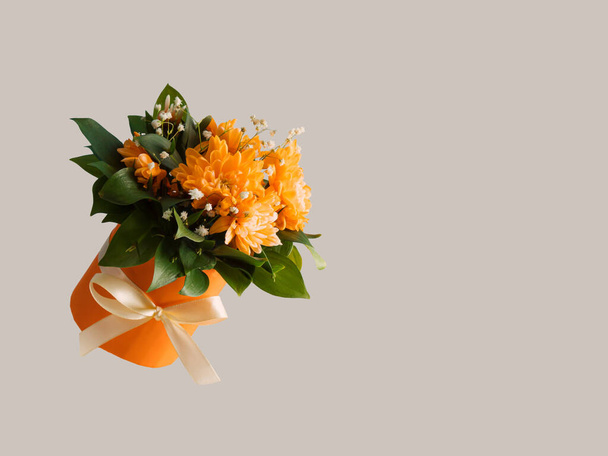 Orange gift box with spring flowers and leaves on grey background. 8 March or Mother's Day card idea. Copy space. - Foto, immagini