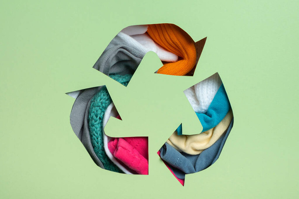 De segunda mano, concepto circular de moda y reciclaje. Ropa colorida bajo papel corte símbolo de reciclaje. - Foto, imagen