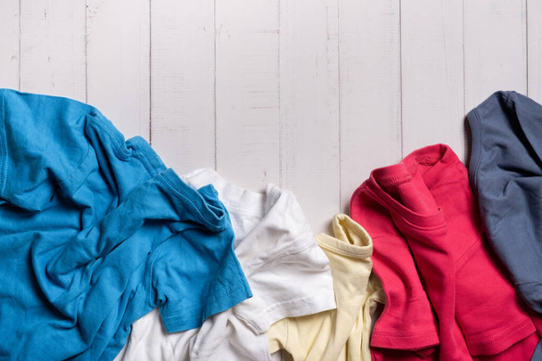 Camisetas coloridas, ropa sobre fondo de madera. De segunda mano, concepto de reciclaje. - Foto, Imagen