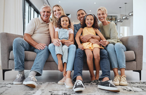 Love, interracial and family on sofa, grandparents and children relax, portrait and happy together. Grandmother, grandfather and girls with mother, father and bonding in living room, smile or weekend. - Foto, Imagem