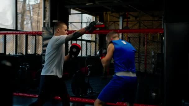 Boxer übt Schläge mit seinem Trainer in Boxsporthalle - Filmmaterial, Video