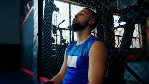 Boxeador cansado después de entrenar duro en el gimnasio con ropa deportiva y guantes de boxeo negro - Metraje, vídeo