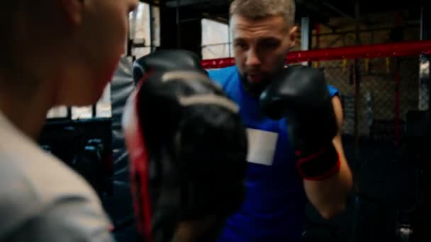 Боксер тренируется со своим тренером в боксёрском зале - Кадры, видео
