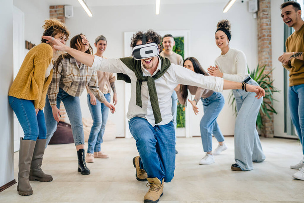 Egy férfi felnőtt kaukázusi férfi előtt a csoport a férfiak és a nők barátai élvezik a virtuális valóság VR headset munka közben szórakozás együtt csapatépítő szeminárium valós emberek fényes szűrő - Fotó, kép