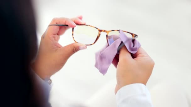 Mains, lunettes et nettoyage avec une opticienne au travail dans son bureau d'optométrie gros plan d'en haut. Lunettes, tissu et vision avec un ophtalmologiste dans une clinique pour essuyer les verres de lunettes de vue. - Séquence, vidéo