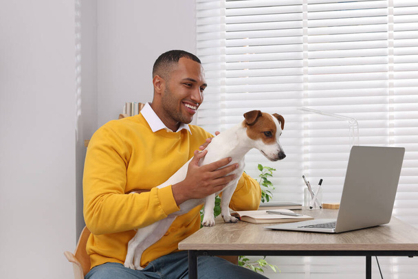 Young man with Jack Russell Terrier at desk in home office - Photo, image