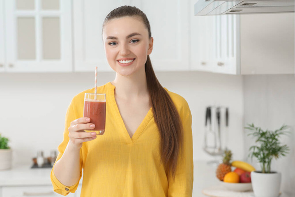 Beautiful young woman with delicious smoothie in kitchen - Zdjęcie, obraz
