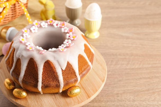 Delicious Easter cake decorated with sprinkles near eggs on wooden table, closeup. Space for text - 写真・画像