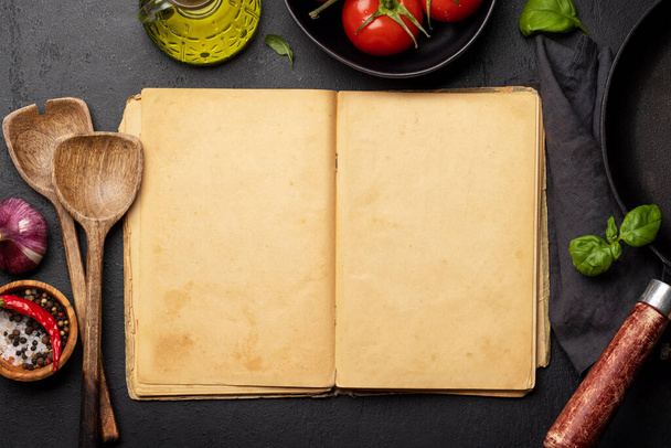 Vista de arriba hacia abajo de una mesa de cocina con ingredientes, utensilios y un libro de cocina abierto con páginas vacías, perfecto para crear una maqueta para recetas o menús - Foto, imagen