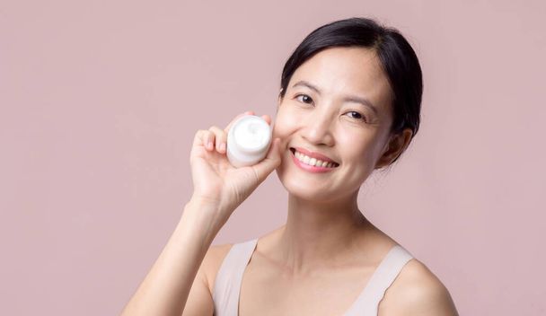Asian young woman with facial skincare face cream, cosmetic moisturiser on healthy natural skin make up face. Portrait glowing smile girl person model with care beauty product, spa, cosmetology. - 写真・画像