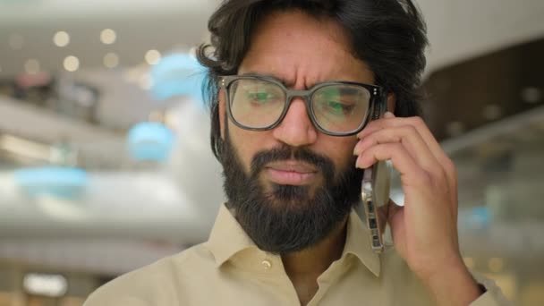 Portrét v kanceláři Arabský muž v brýlích mluvící telefonicky odpovědět obchodní hovor. close up vážný indický muž podnikatel výkonný podnikatel mluvit vzdálený komunikace mluvit mobilní konverzace - Záběry, video
