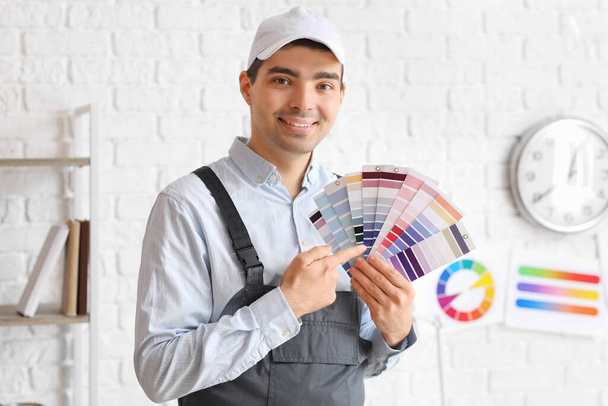 Male painter pointing at color palettes in room - Фото, изображение
