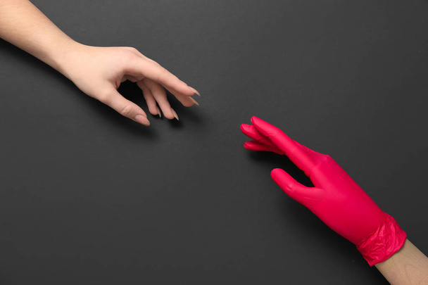Woman and wooden hand in rubber glove on black background - Foto, Imagen