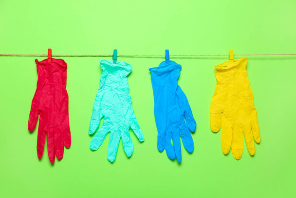 Seil mit Wäscheklammern und Medizinhandschuhen auf grünem Hintergrund - Foto, Bild