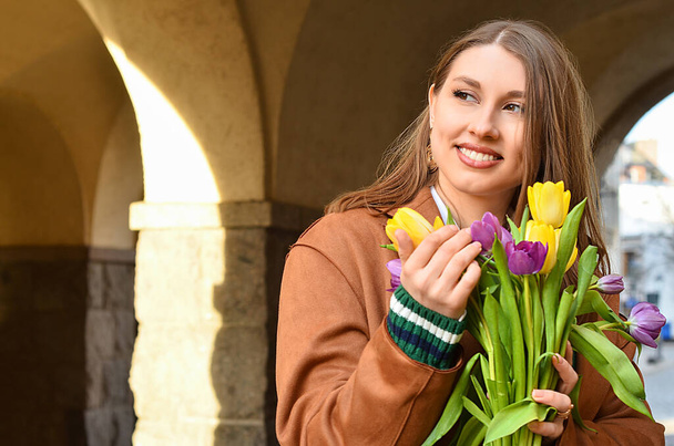 Young woman with tulips on city street, closeup - Foto, Bild