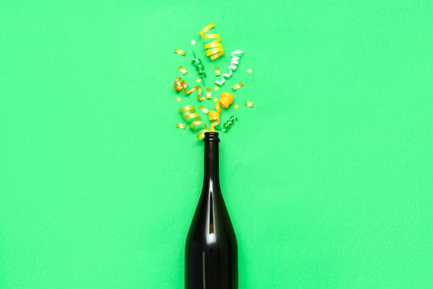 Composition with champagne bottle and confetti on green background - 写真・画像