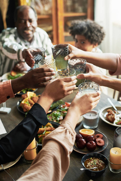 Detailní záběr rodinné toasting s sklenicemi nápojů při posezení u jídelního stolu při večeři - Fotografie, Obrázek