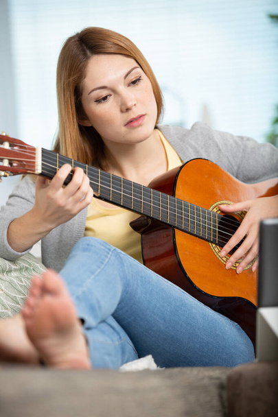 woman with tablet computer sitting play acoustic guitar at home - Foto, afbeelding