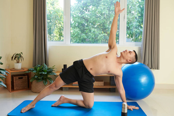 Ajuste joven fuerte ejercitar en casa por la mañana para mejorar la fuerza y la flexibilidad - Foto, imagen
