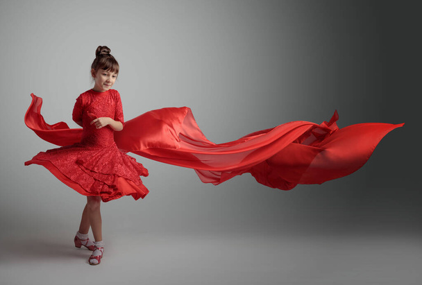 Kırmızı elbiseli, uçan kırmızı saten kumaşlı dansçı kız. Boşluğu kopyala. - Fotoğraf, Görsel