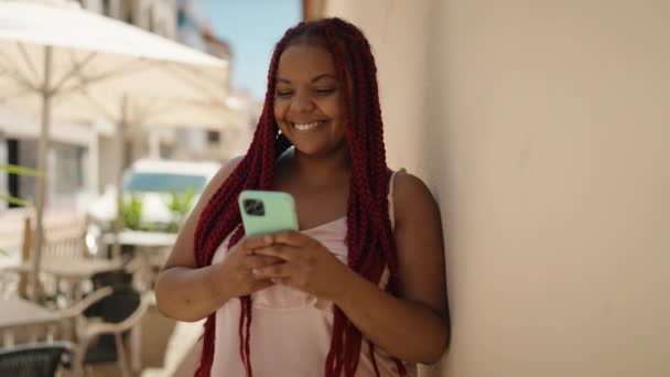 Afrikai amerikai nő mosolygós magabiztos segítségével smartphone az utcán - Felvétel, videó