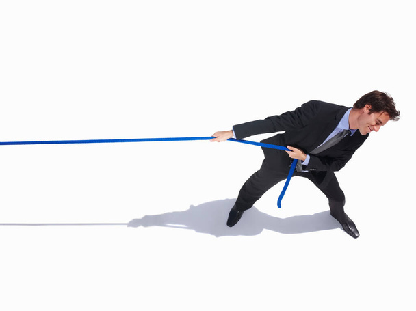 Un jeune homme d'affaires tirant une corde sur blanc. Un jeune homme d'affaires tirant une corde avec copyspace sur blanc - Photo, image