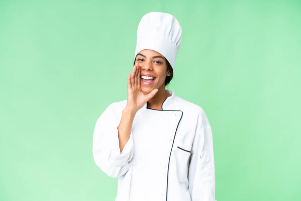 Молодой афро-американский шеф-повар на изолированном фоне хромы кричит с открытым ртом - Фото, изображение