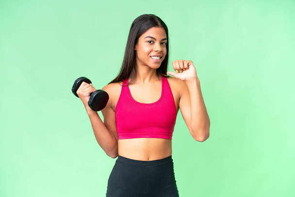 jovem afro-americano mulher esporte mulher fazendo levantamento de peso sobre isolado croma chave fundo orgulhoso e auto-satisfeito - Foto, Imagem