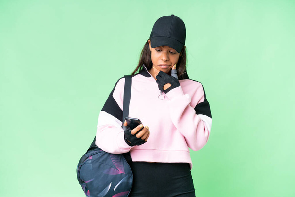 Jovem esporte afro-americano mulher com saco de desporto sobre isolado croma chave fundo pensando e enviando uma mensagem - Foto, Imagem